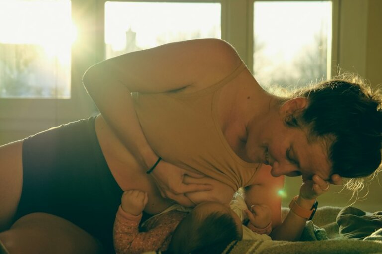 Mutter hält ihr Baby morgens nach dem Aufwachen im hellen Schlafzimmer