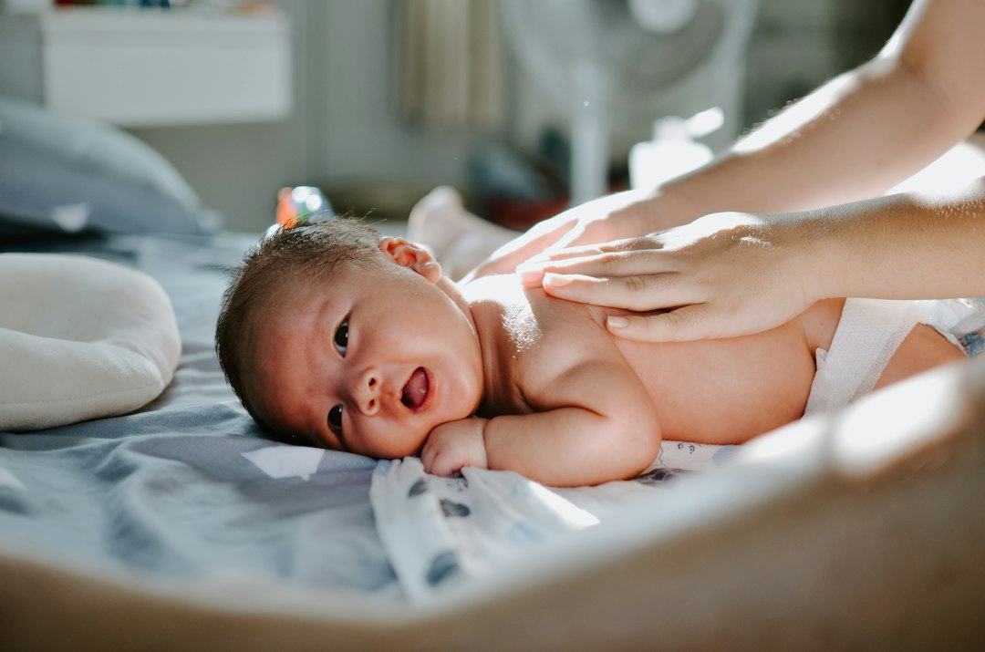 Baby auf heller Unterlage bei sanfter Hautpflege als Motiv zur Pflege im Windelbereich