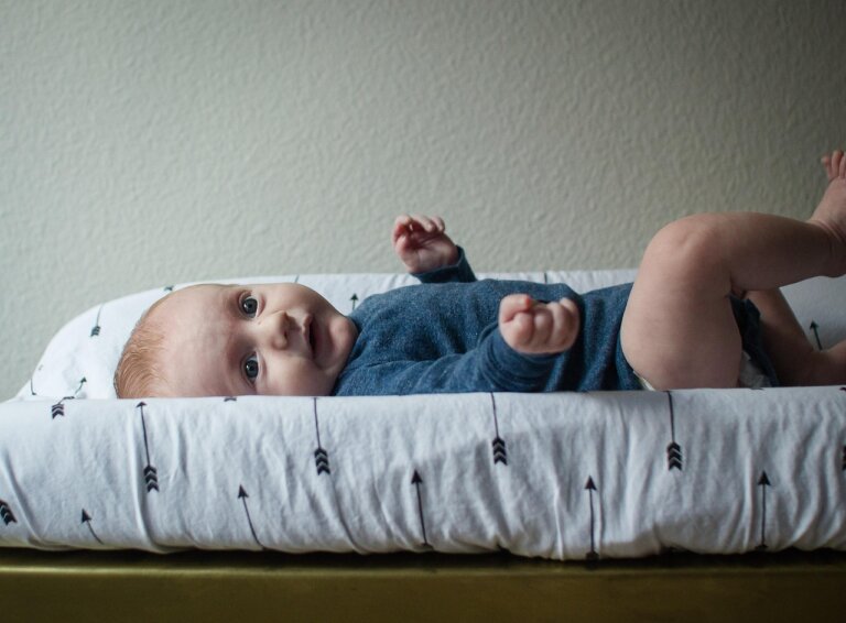 Baby auf einer Wickelauflage als Symbol für die doppelte Bedeutung von Windelfrei