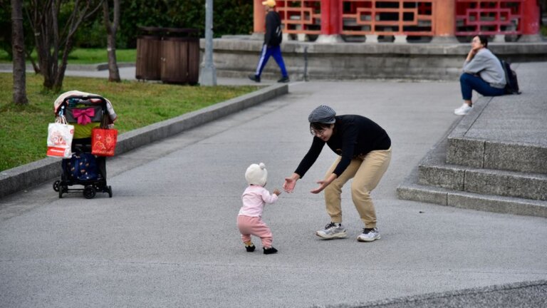 Mutter und Kleinkind mit Kinderwagen bei einem Ausflug im Park