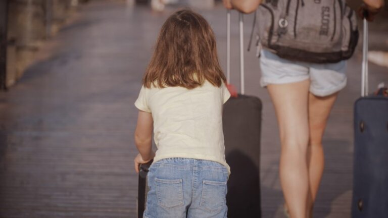 Mutter und Kind sind mit Gepäck unterwegs in den Urlaub