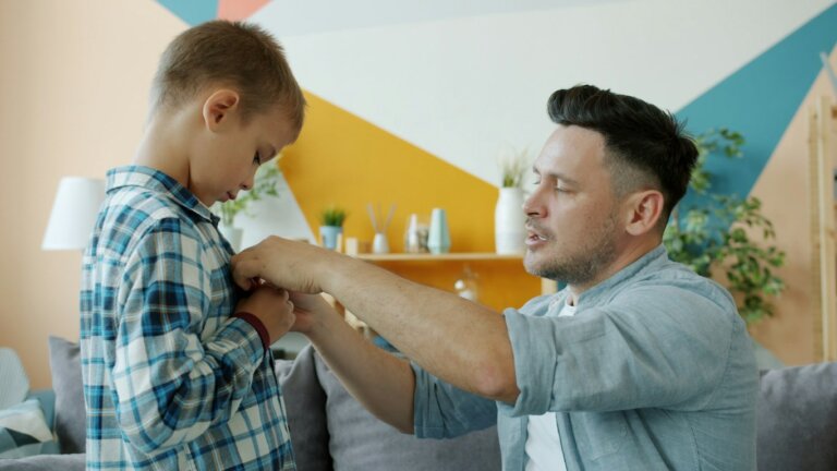Vater hilft seinem Kind beim Anziehen als Symbol für zunehmende Selbstständigkeit beim Trockenwerden